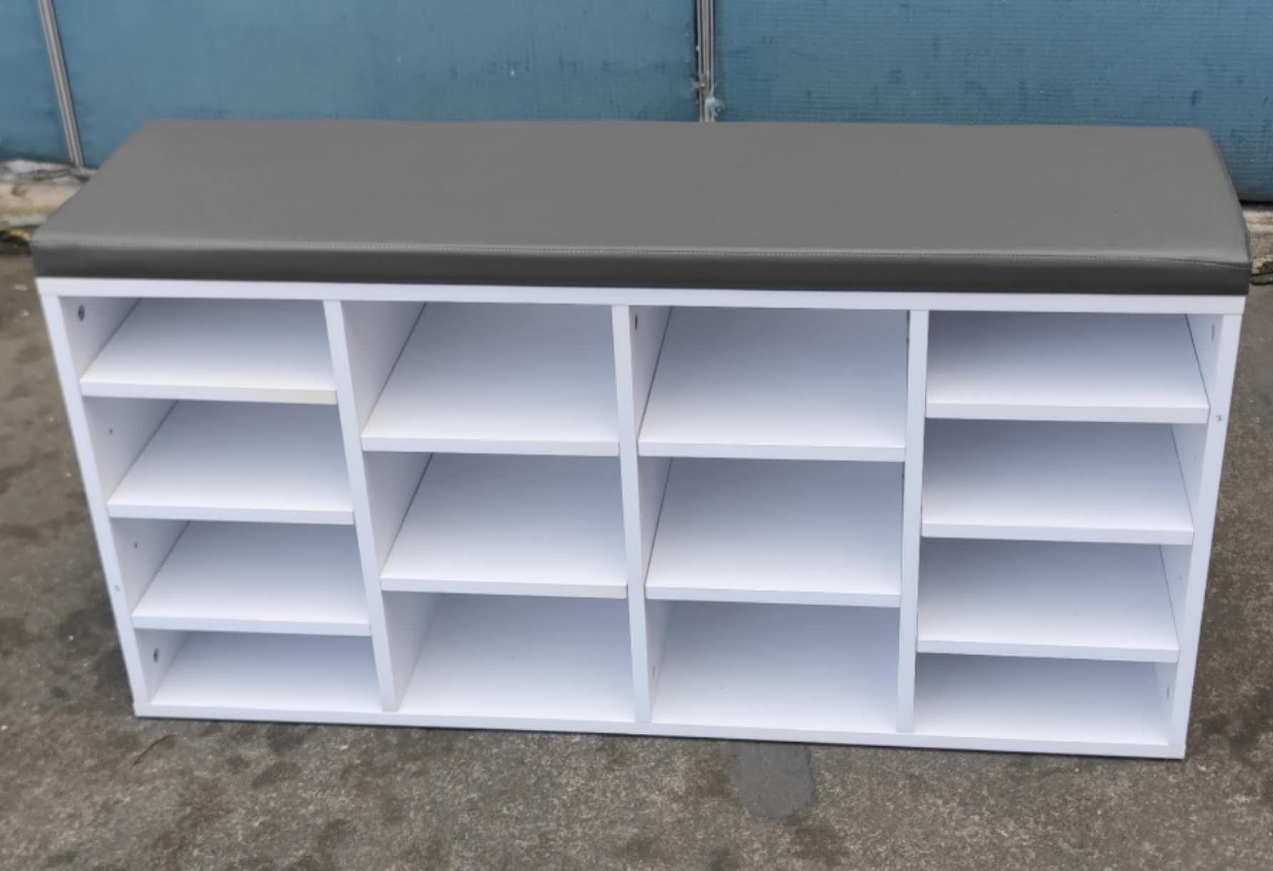 White shelving unit with a gray top against a blue wall.
