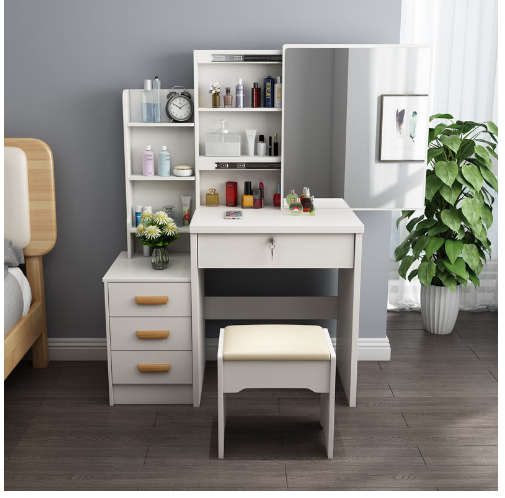 A modern white dressing table with a mirror and a stool, featuring three drawers and yellow handles, placed in a room with a window and a plant.