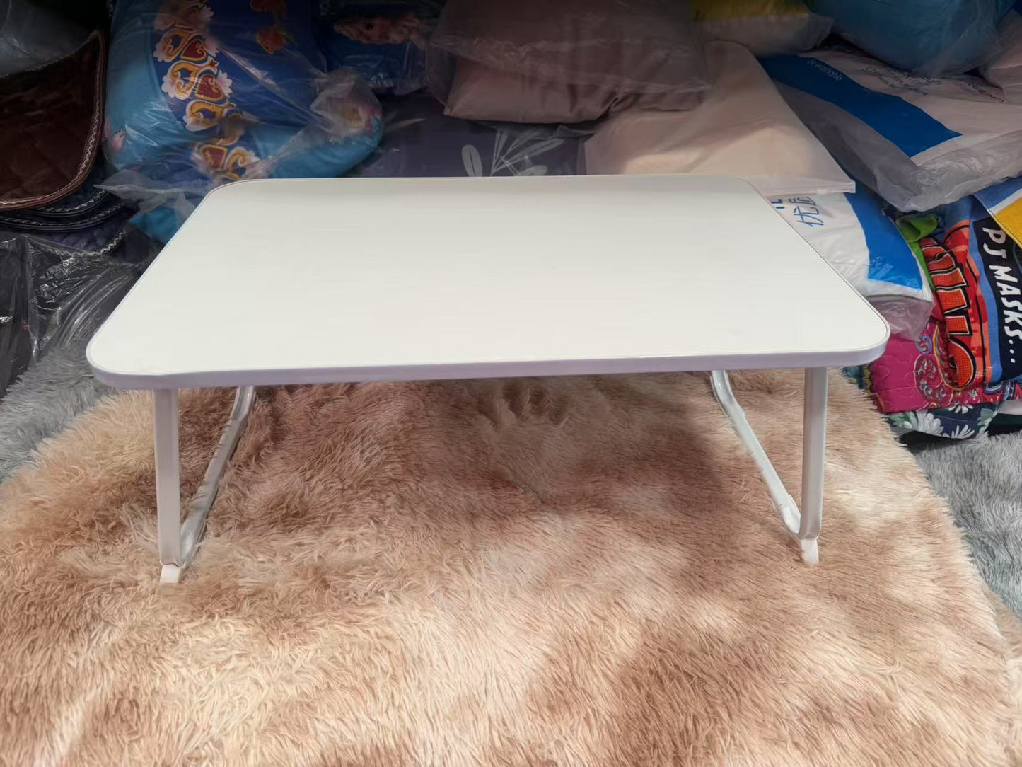 A portable folding table with white tabletop and black foldable legs, 