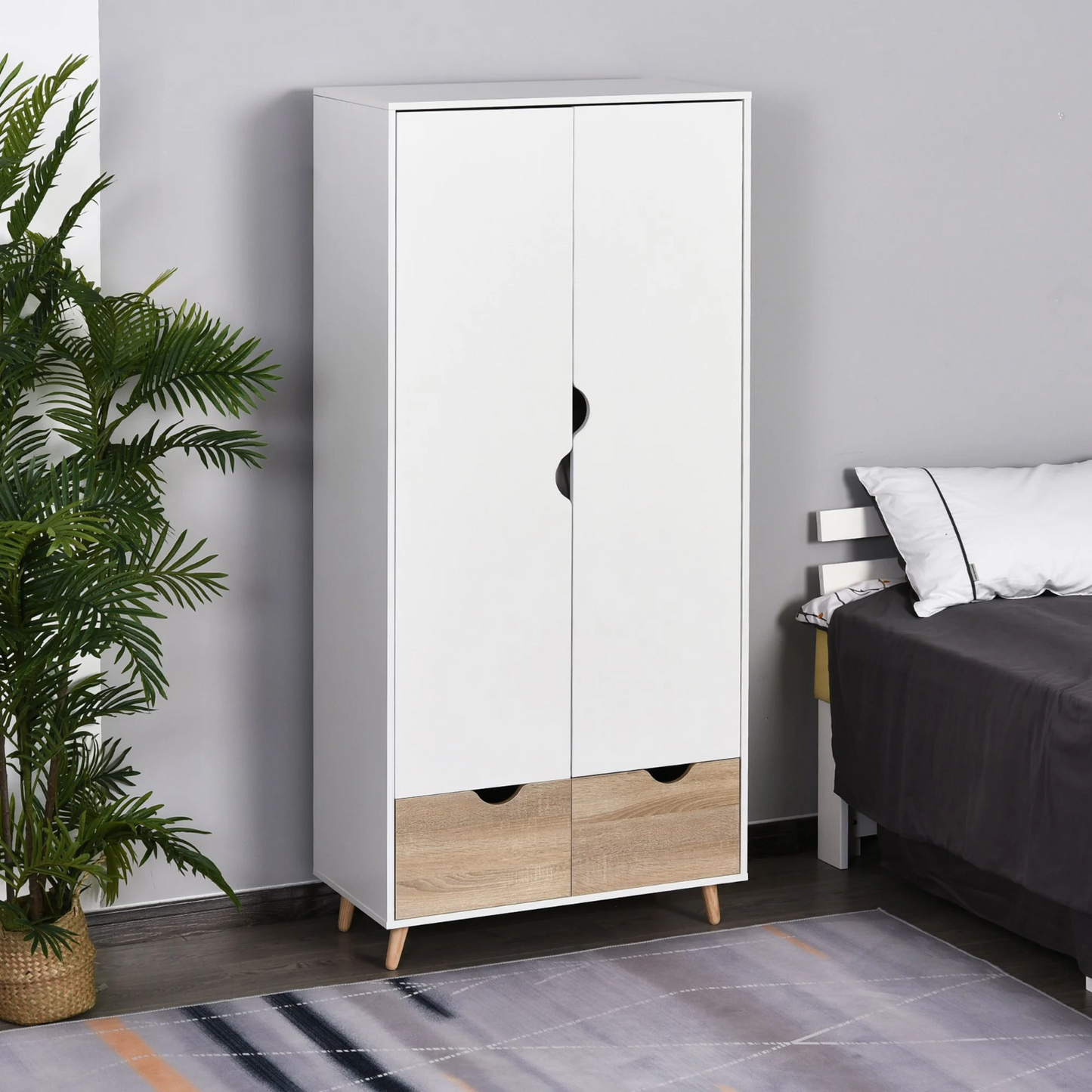A modern white wardrobe with two doors and two drawers, placed in a room with a bed and a potted plant in the background.